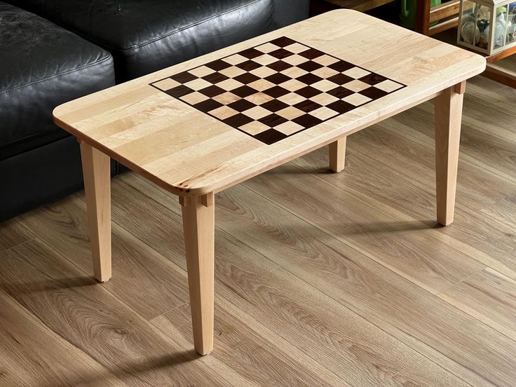 a coffee table with a chess board design on it in front of a black couch