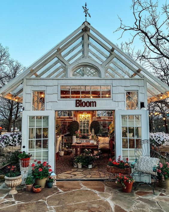 a white building with lots of windows and potted plants in front of it that says bloom