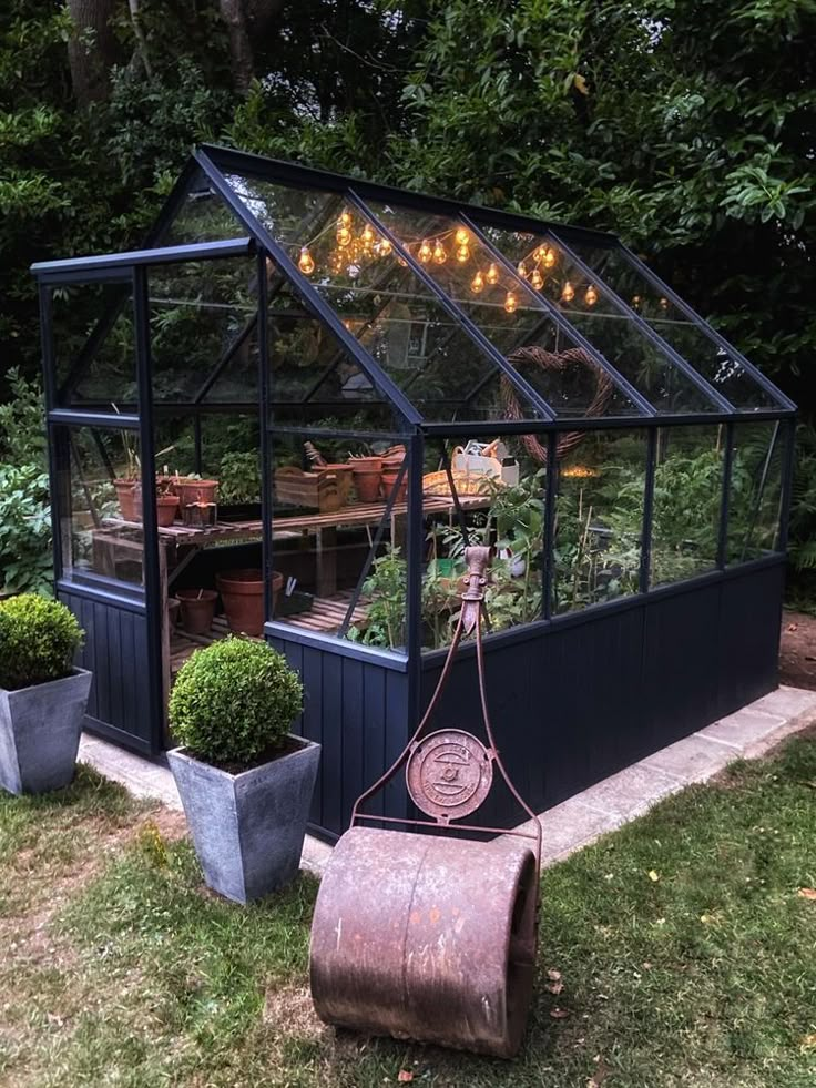 a small greenhouse with potted plants and lights on the roof is set up outside