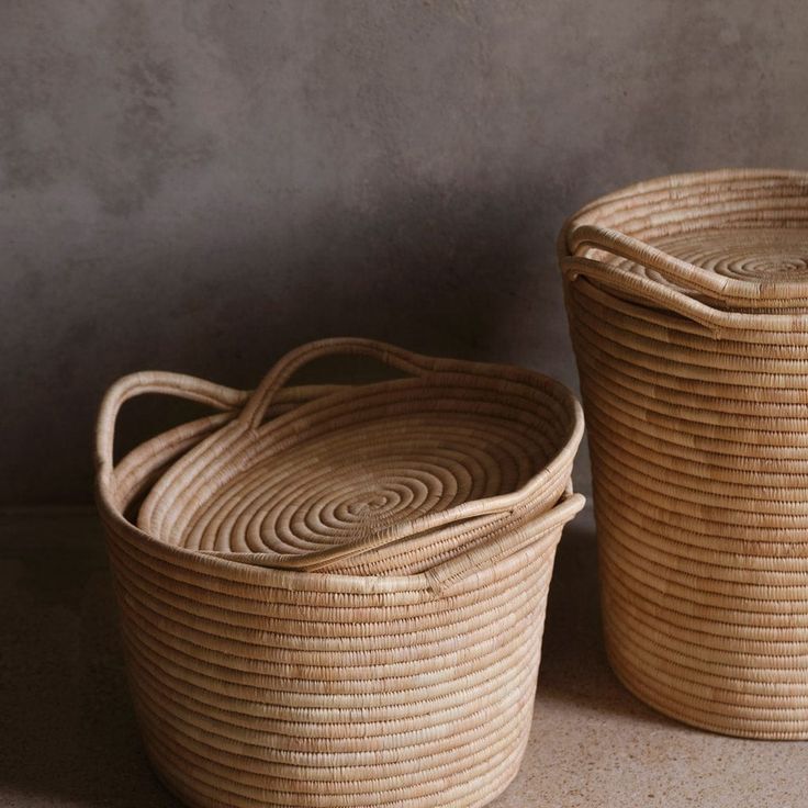 two woven baskets sitting next to each other on the floor in front of a wall