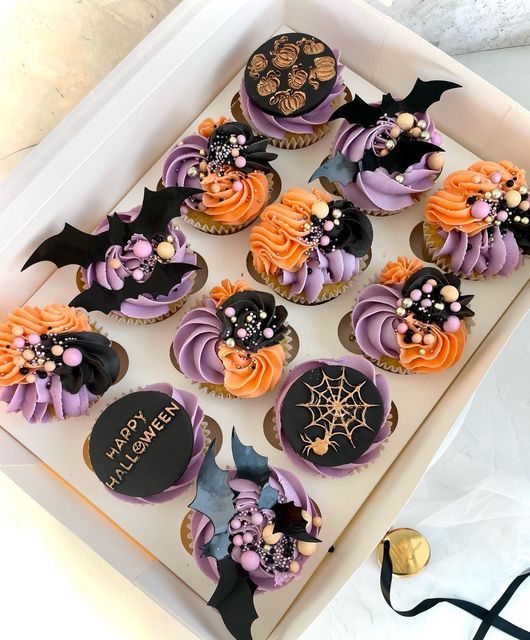 cupcakes decorated with purple and orange frosting in a box on a table