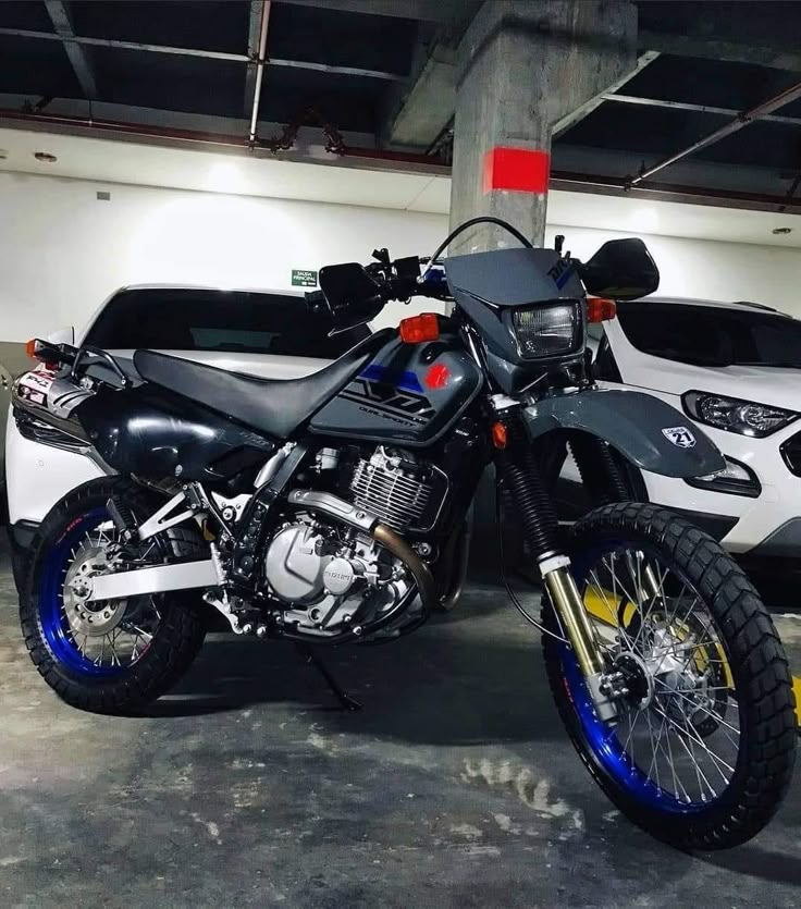 a motorcycle parked in a parking garage next to two other vehicles on the ground and one has blue rims