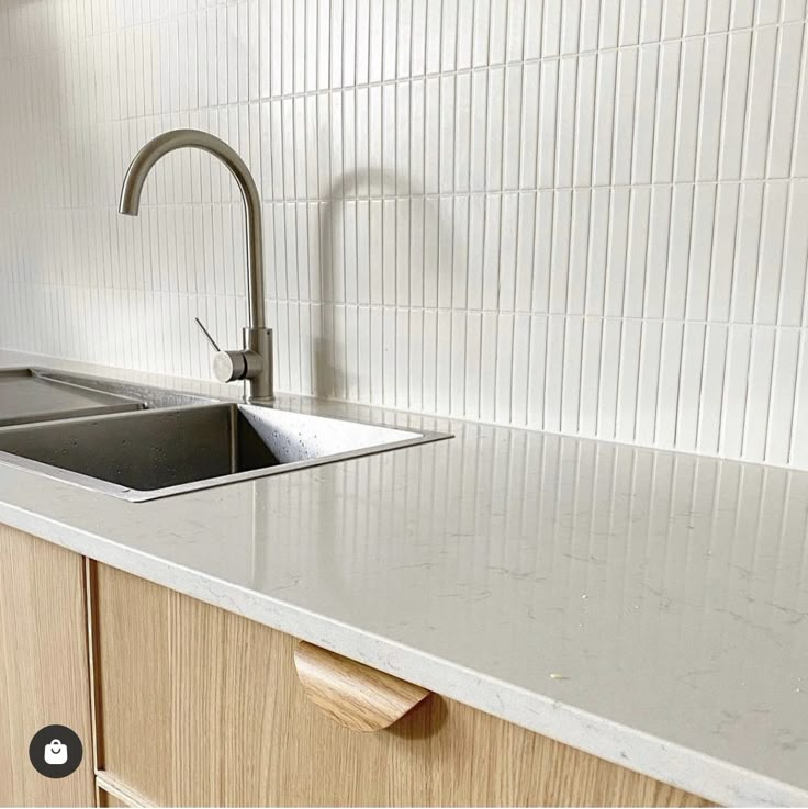 a kitchen sink sitting under a faucet next to a counter top with a wooden cabinet