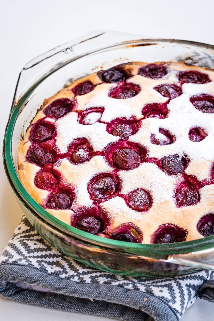 a dessert dish with strawberries and powdered sugar in the center, on a table