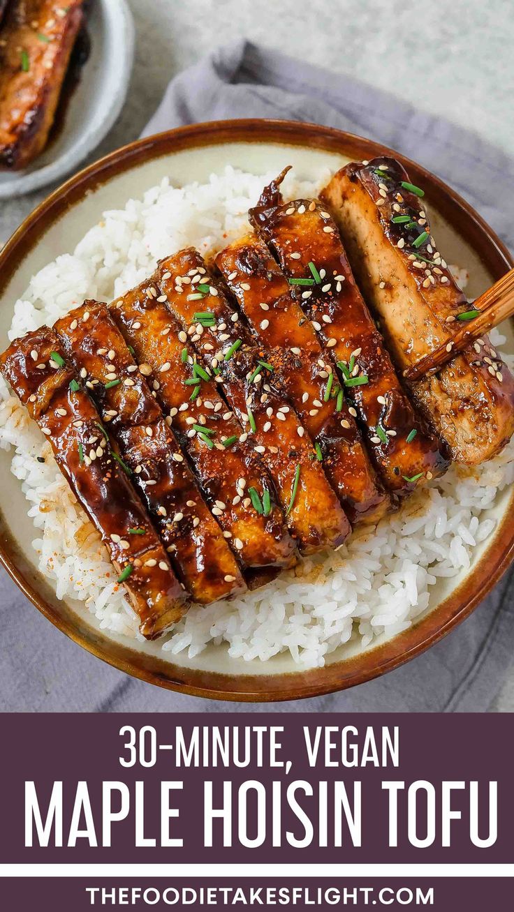 a plate with tofu on top of rice and chopsticks in the middle