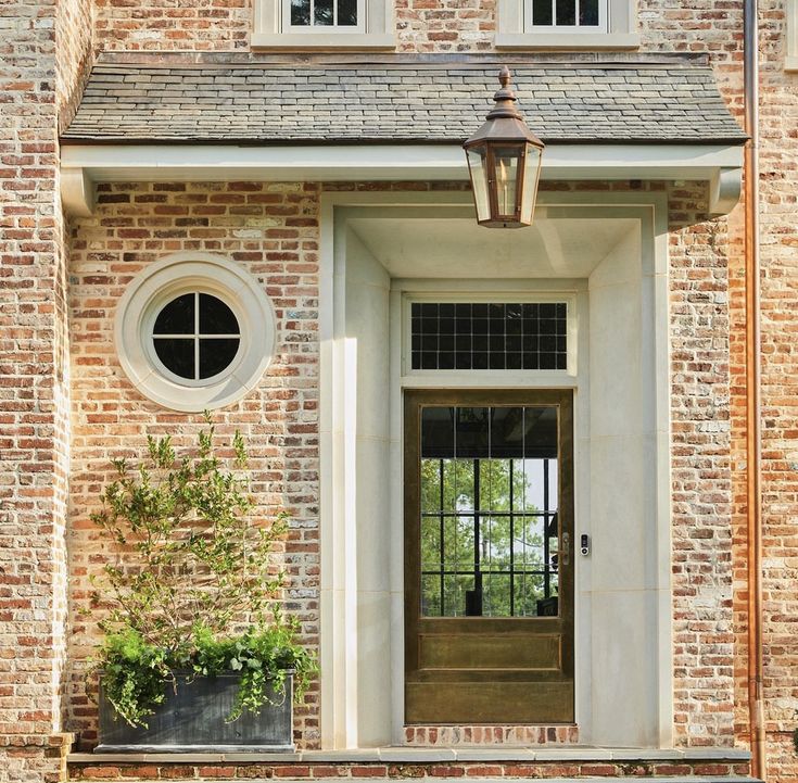 a brick building with two windows and a lamp on the front door is seen in this image