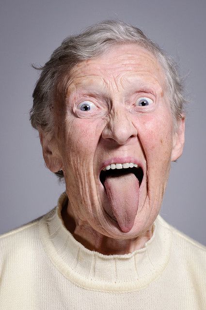 an old man making a funny face with his tongue out and eyes wide open,