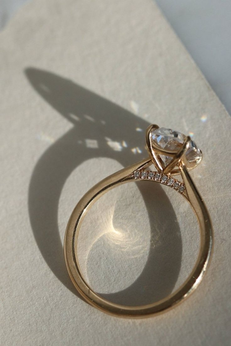 a gold ring with a diamond on it sitting on top of a piece of paper