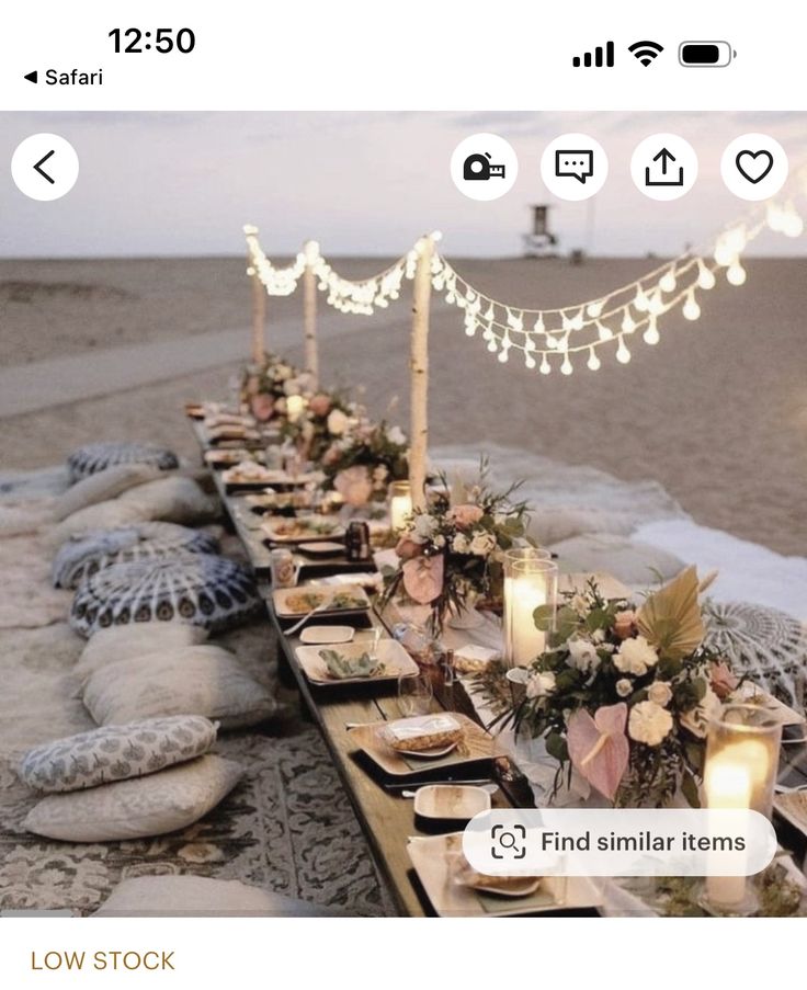 a long table is set up on the beach with candles and place settings for dinner