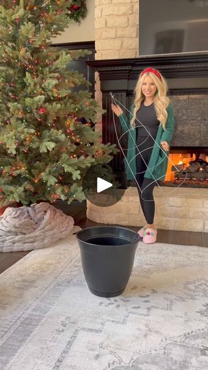 a woman is standing in front of a christmas tree with her hands out to the side