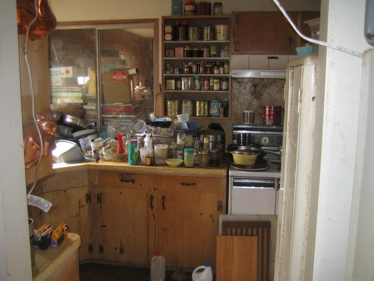 a kitchen with lots of clutter on the counter and shelves full of cooking utensils