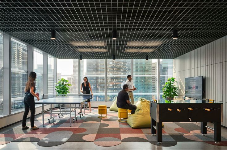 three people are standing in an office with large windows looking out on the city skyline