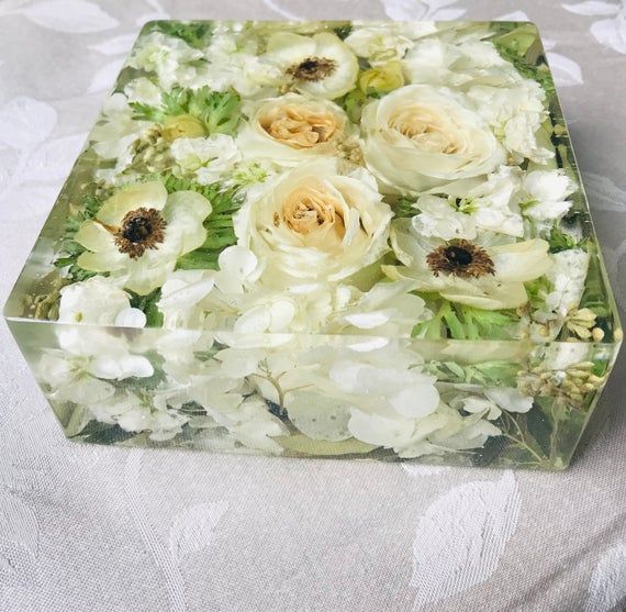 a glass box filled with white and yellow flowers