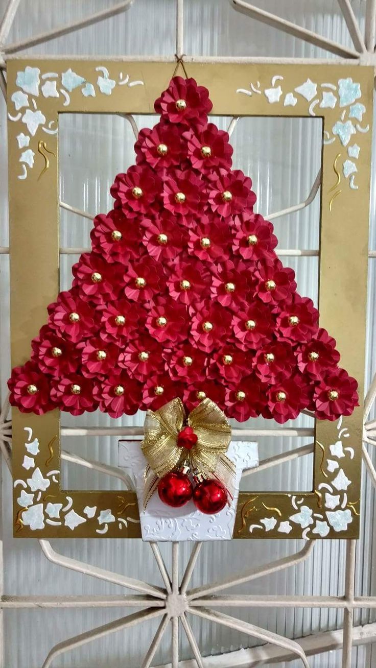 a christmas tree made out of red flowers and gold ribbon with a bow on top