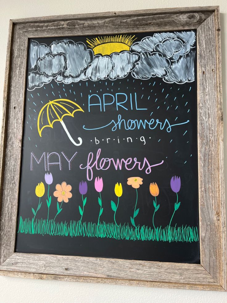 a chalkboard with flowers and an umbrella on it that says, april showers bring mayflowers