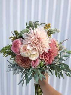 a person holding a bouquet of flowers in their hand with white and pink petals on it