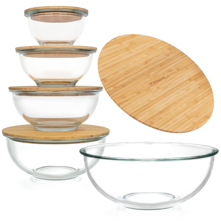 glass bowls with bamboo lids and wooden cutting board in front of them on a white background