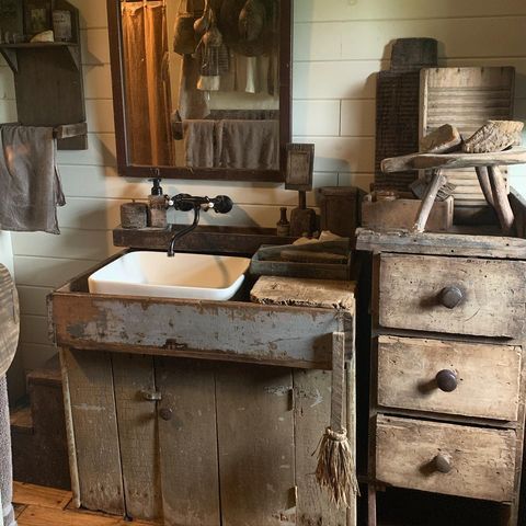 an old fashioned sink and cabinet in a rustic bathroom with wood floors, white walls and wooden flooring