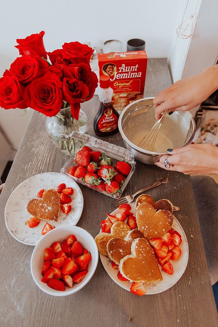 the table is covered with heart shaped pancakes and strawberries