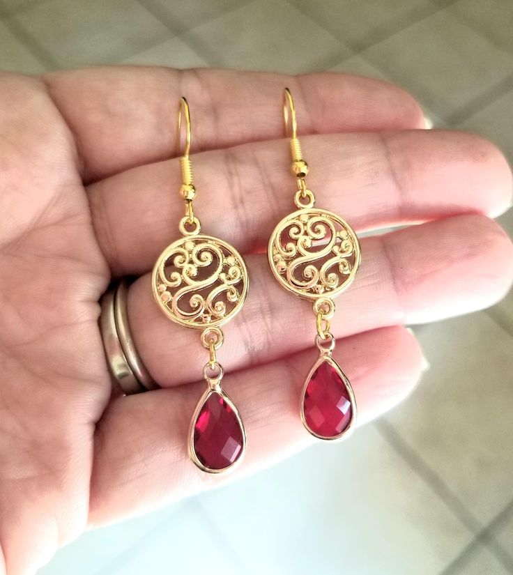 New Handmade Ruby Teardrop Dangle Earrings In each 14Kt yellow gold dangle earring, a pear-shaped Ruby is beautifully set in a bezel setting. These July birthstone earrings are the perfect accent for any occasion ~ Multi faceted stone captures light brilliantly  ~ Drop length measures 2 inches ~ Barrel cut Australian Crystal Ruby teardrop charms ~ Filigree circle charm ~ 14k gold over sterling silver ear hooks stamped .925 ~ Hypoallergenic  ☆I ship daily Monday-Saturday☆ Gift Packaging & Message Red Teardrop Chandelier Earrings As Gift, Red Chandelier Earrings As Gift, Red Teardrop Chandelier Earrings With Ear Wire, Red Teardrop Chandelier Earrings, Red Nickel-free Chandelier Earrings As Gift, Red Elegant Nickel-free Teardrop Earrings, Red Pierced Dangle Chandelier Earrings, Nickel Free Elegant Red Chandelier Earrings, Red Dangle Chandelier Earrings