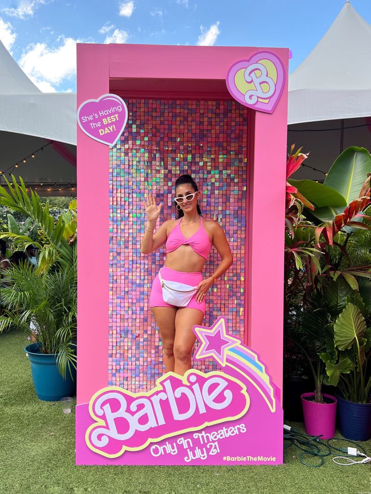 a woman in a pink bathing suit posing for a photo inside a barbie doll display