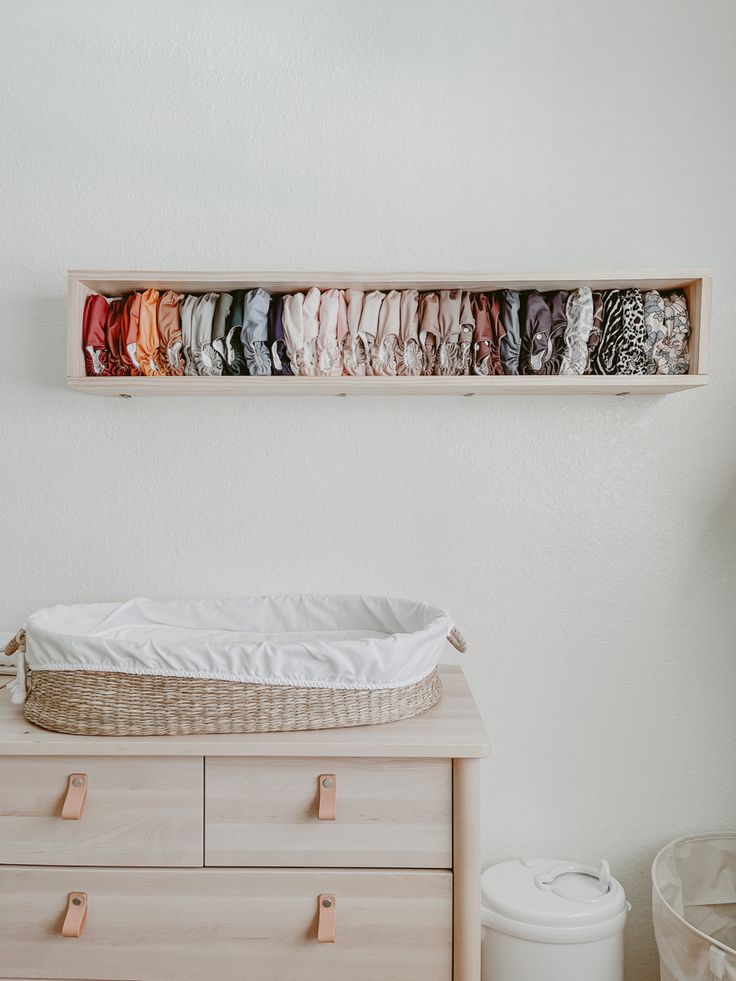 a baby crib in front of a wall with clothes hanging on it's shelves