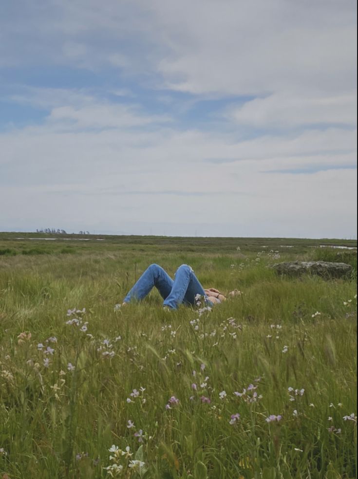 a person laying down in the middle of a field