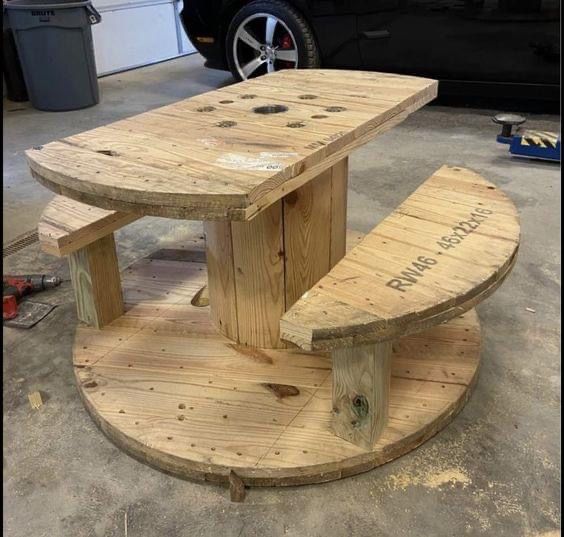 a wooden bench sitting on top of a pallet in front of a black car