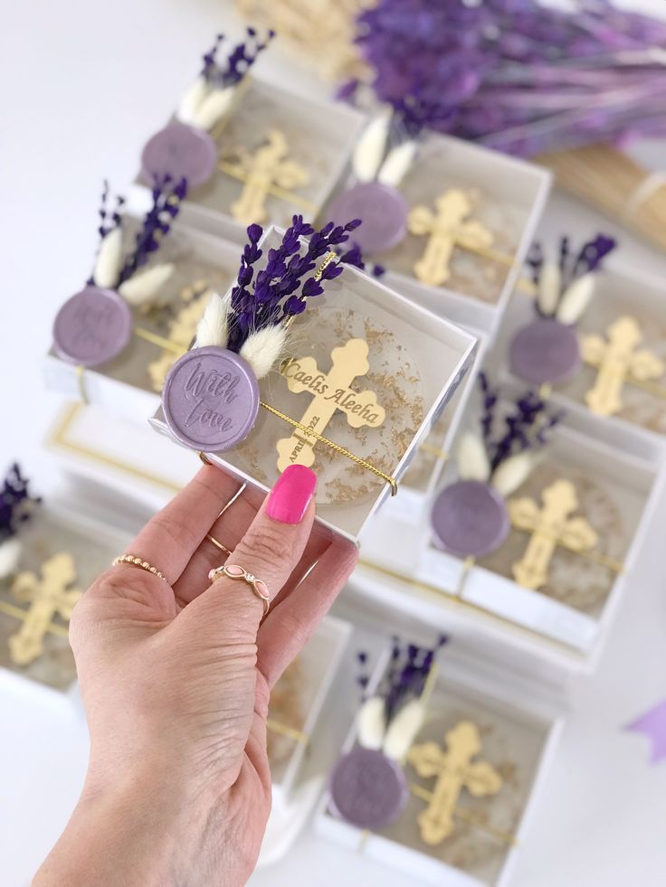 a person holding up a small box with purple and white decorations on top of it