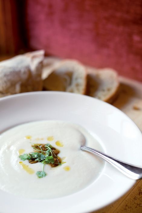 a white plate topped with soup next to slices of bread