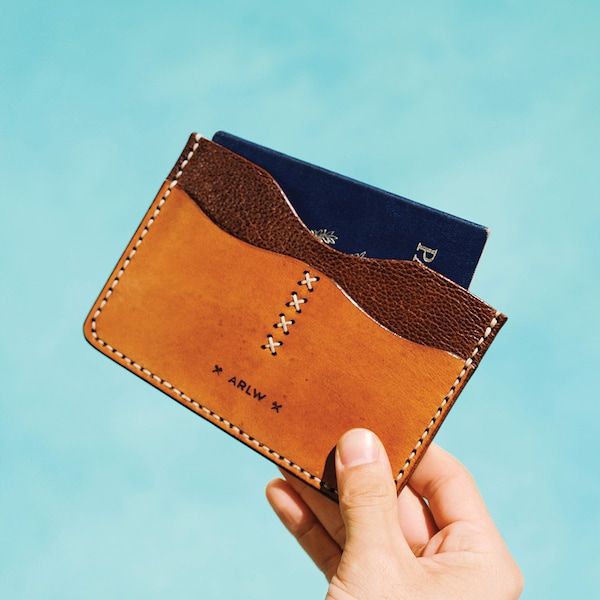 a hand holding up a wallet with two credit cards sticking out of the front pocket