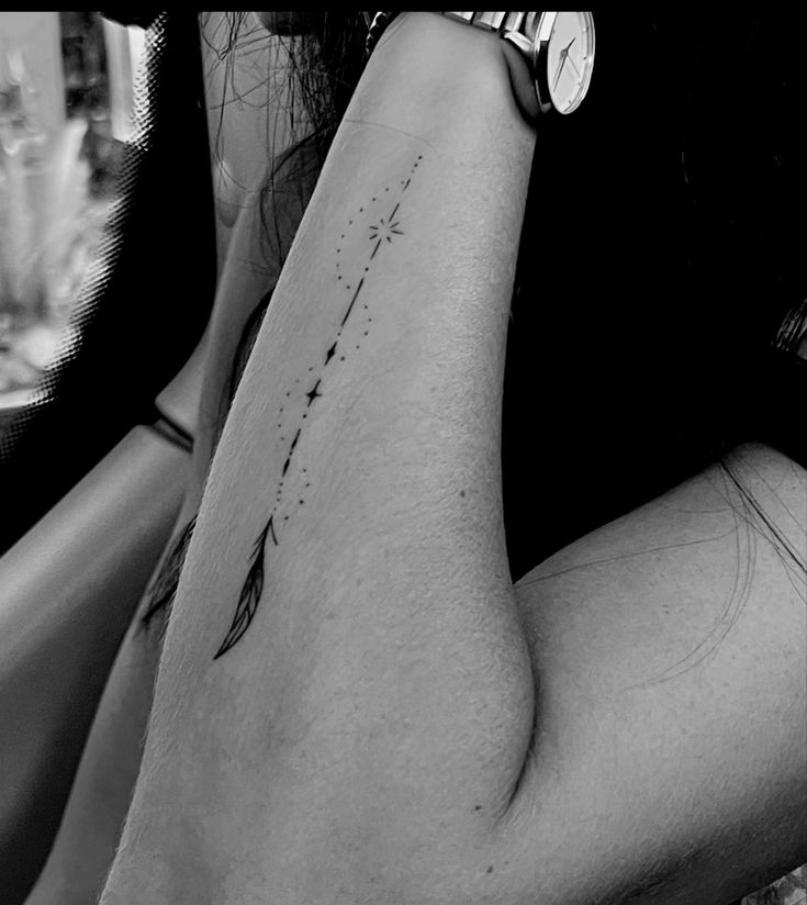 black and white photograph of a woman's arm with an arrow tattoo on it