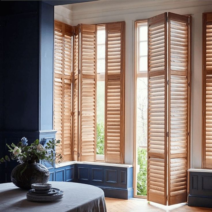 an empty room with wooden shutters on the windows and a table in front of it