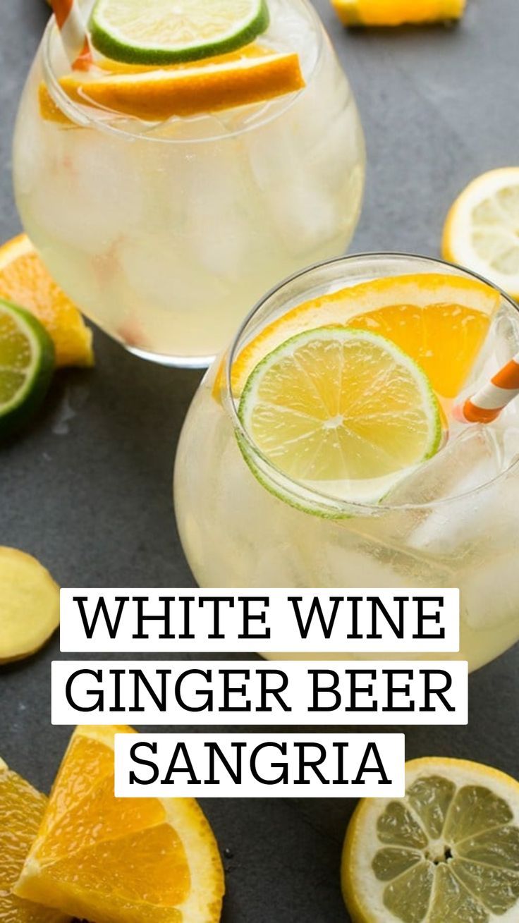 white wine ginger beer sangria with orange slices and limes in the background text reads, white wine ginger beer sangria