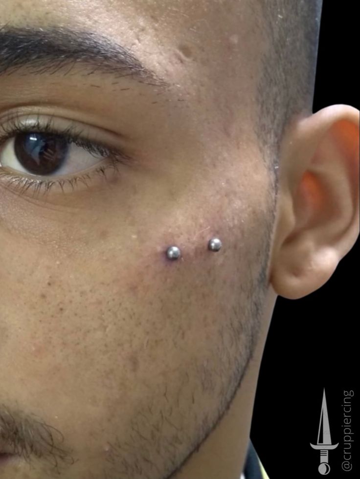 a man with piercings on his nose looking at the camera