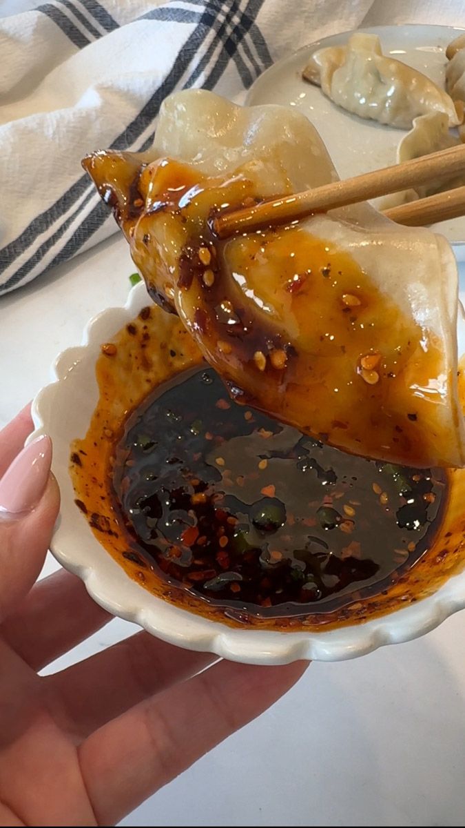 a person holding a plate with food on it and chopsticks in the bowl