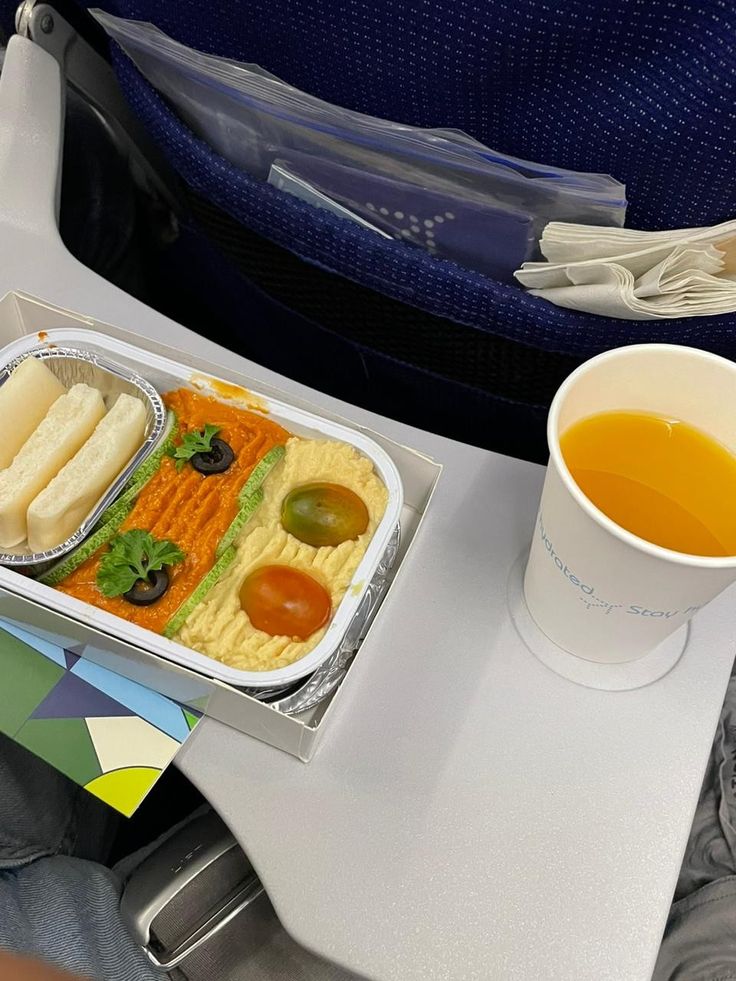 an airplane tray with food and drink on the table next to its seatbelts