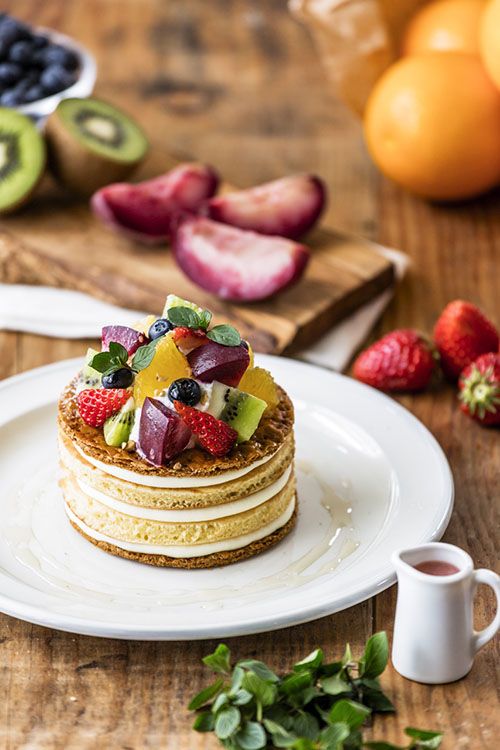 a stack of pancakes topped with fruit on top of a white plate