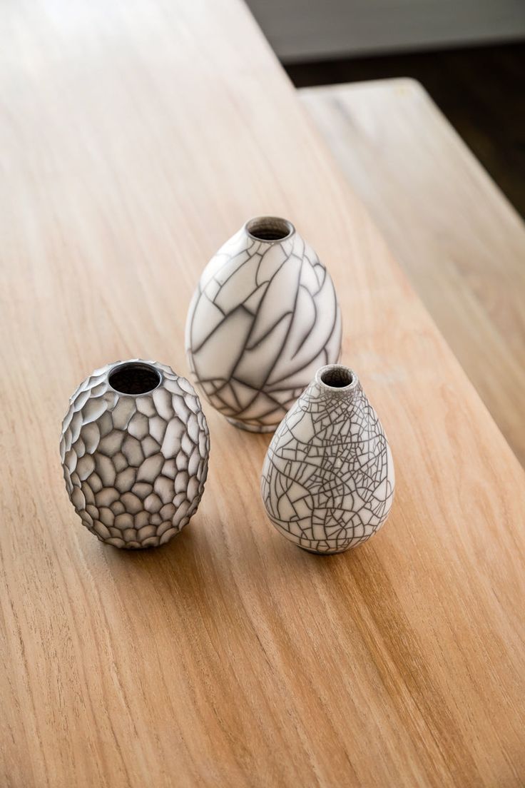 three white vases sitting on top of a wooden table