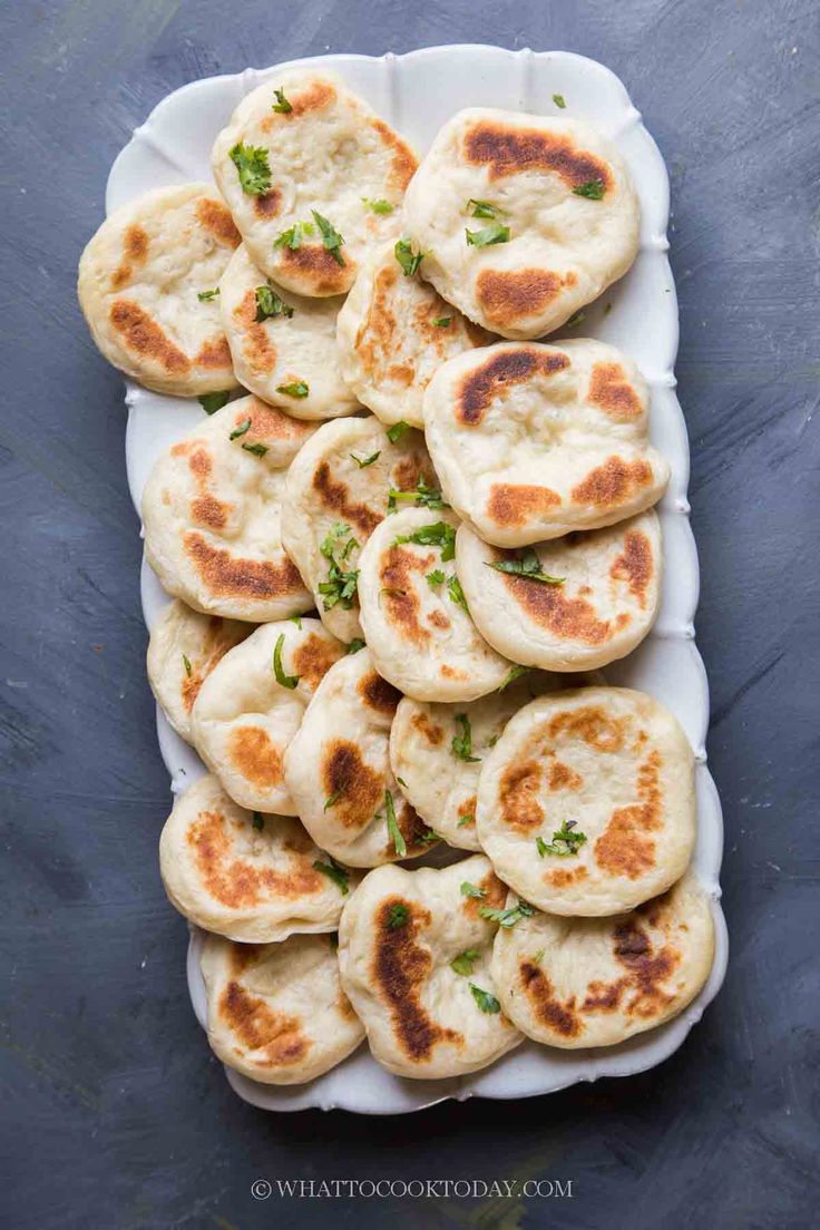 small flat breads on a white plate with green garnish