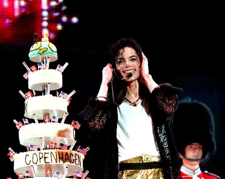 a woman standing next to a cake on top of a stage