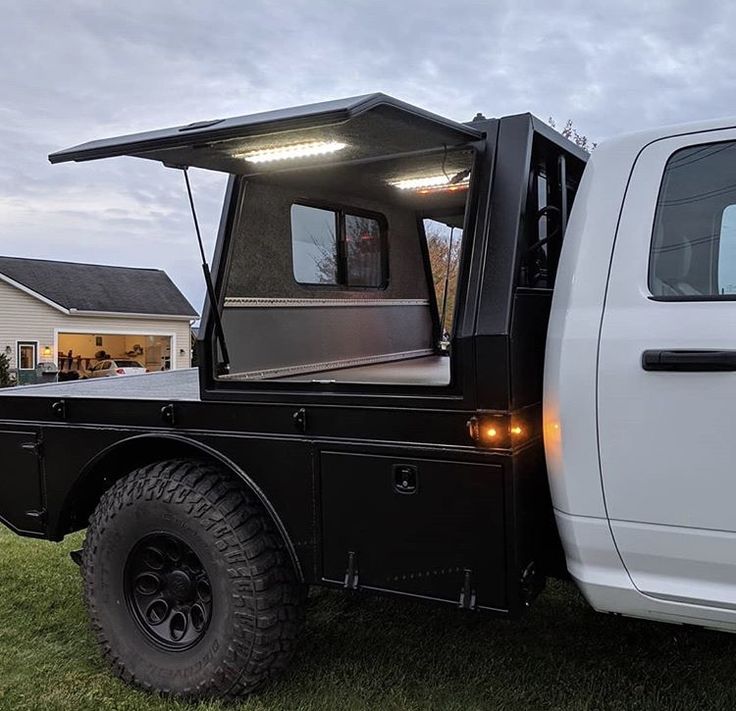 a white truck parked in the grass with its door open and lights on it's side