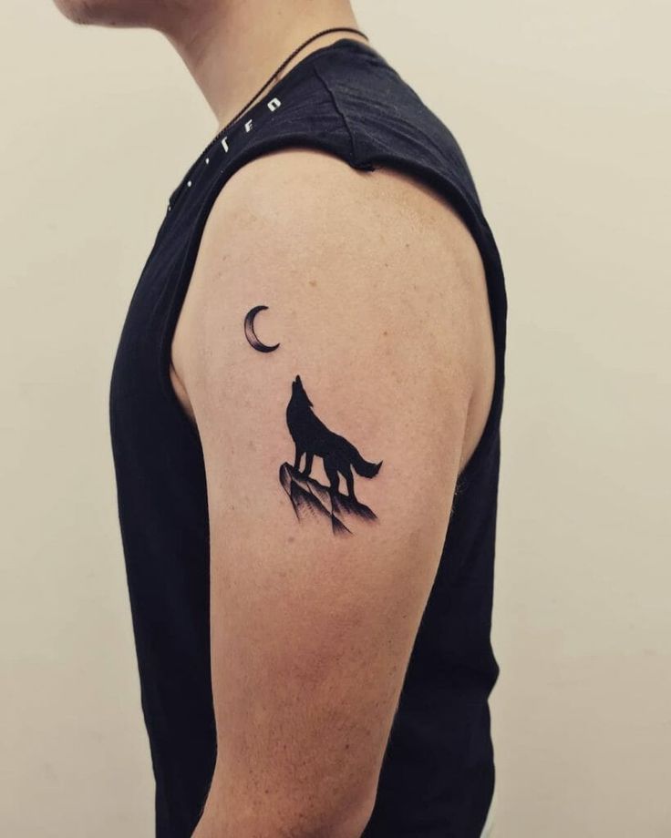 a man's arm with a wolf tattoo on it and the moon in the background