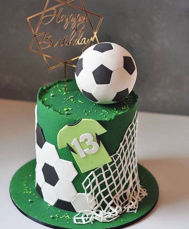 a green and white cake with soccer balls on top