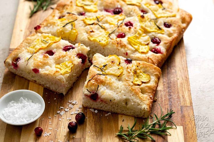 a wooden cutting board topped with slices of bread and cranberry toppings on top of it