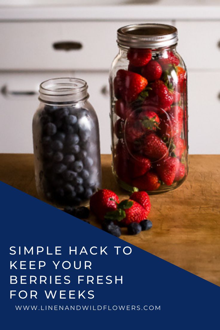 two jars filled with berries sitting on top of a wooden table