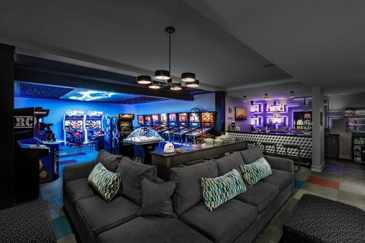 a living room filled with lots of furniture next to a bar and slot machines on the wall