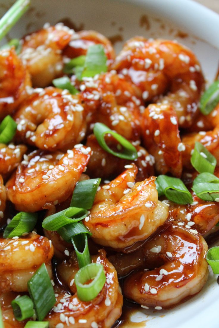 a white bowl filled with shrimp and sesame seed sprinkled on top of it