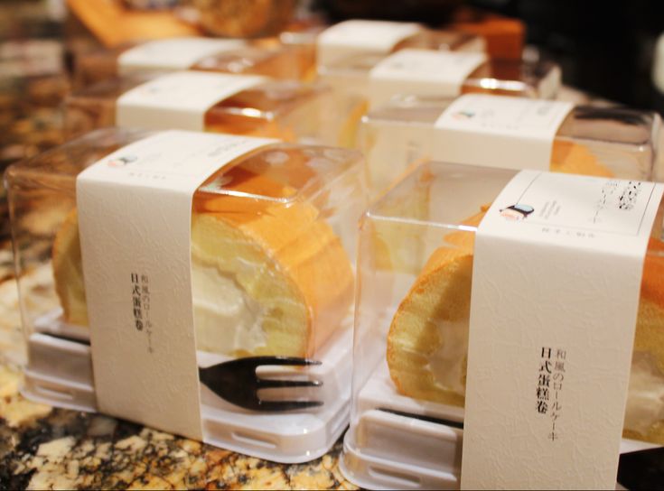 there are many different types of pastries in the box on this counter top, with forks sticking out of them