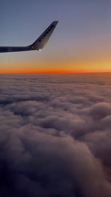 an airplane flying above the clouds at sunset